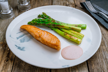 Salmon steak on the grill with asparagus on wooden table