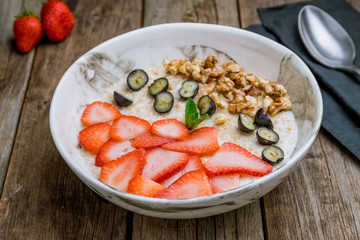 Oatmeal with berries and walnuts on wooden table