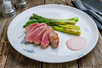 grilled tuna fillet with asparagus on wooden table