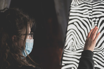  side view of a young woman with long hair wearing a surgical mask
