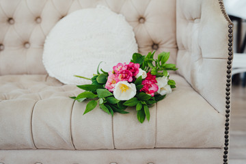A bouquet of flowers lies on a beige sofa.