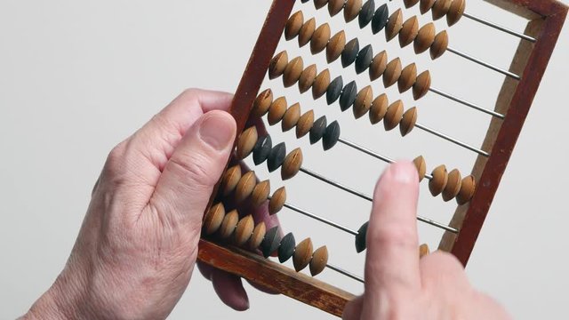 A Elderly Man Is Holding And Moves Wooden Knuckles On A Outdated Vintage Wooden Abacus On A White Background, Close-up On The Right Side.