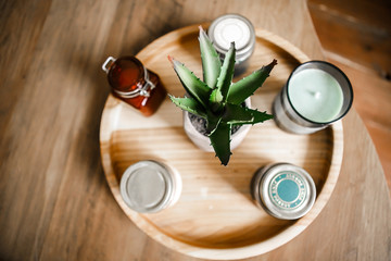 Interior items: candles, aromatic sachets, aloe flower on a wooden round stand on a wooden table.
