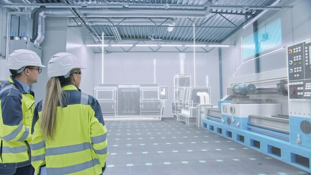Two Engineers Standing and Talking in Factory Workshop with AR Creating 3D Models CNC Machinery Production Line. Industry 4.0 Graphics Visualization in Factory. Arc Shot. VFX Special Visual Effects