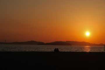 渋川海岸の夕日とカップルのシルエット