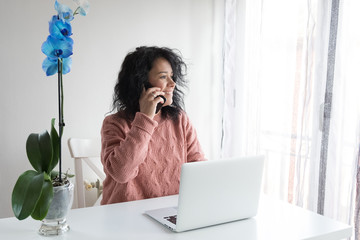 Woman works from home with the computer talking on the phone