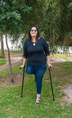 Young beautiful amputee woman walking with crutches