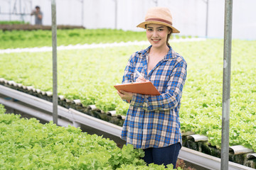 Obraz premium Asian female farmers work in greenhouse hydroponic organic, Agriculture and healthy food Concept.