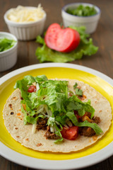 Yellow plate with mexican speciality beef tacos on a wooden table