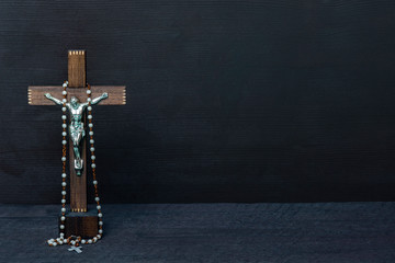 Christian cross and rosary beads on wooden vintage background