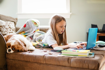 Grade school girl digital distance learning homeschooling on laptop at home
