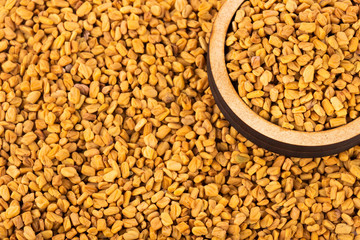 Organic fenugreek seeds in wooden bowl - Trigonella foenum - graecum