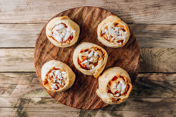 Rolled buns with apple and coconut paste on wooden cutting board with herbal tea. Quick puff pastry for breakfast.