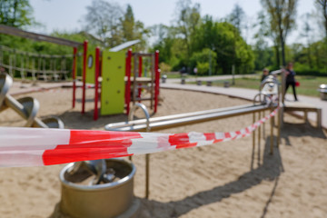 Fototapeta na wymiar Close up view,Red and white alarm caution tape wrapped around closed outdoor playground toys during global quarantine from COVID-19. Lockdown and quarantine time in epidemic of COVID-19 Virus crisis.