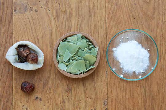 Flat Lay Overhead Shot Of Aleppo Soap, Baking Soda And Accessories For Laundry Like Soapberries On A Wooden Background.