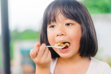 Thai kid little girl eat roti sweet dessert very famous in Thailand.Hungry face and enjoy eating concept.Little asian girl enjoy eating with Homemade fresh wheat flour Chapati.