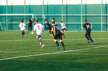 Boys in  white black sportswear running on soccer field. Young footballers dribble and kick football ball in game. Training, active lifestyle, sport, children activity concept