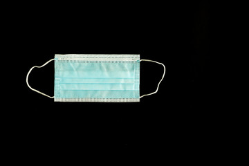 A surgical face mask isolated on a black background