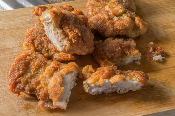 Boneless breaded chicken legs on a wooden cutting board, crispy and ready to serve, mouth-watering food concept