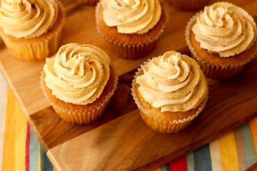Snickerdoodle cupcakes with cinnamon swirl frosting sitting on a wooden and tablecloth setup