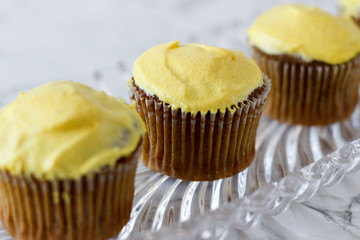 Spice cupcakes sitting on a glass tray next to a household lamp