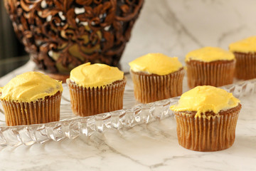 Spice cupcakes sitting on a glass tray next to a household lamp