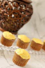Spice cupcakes sitting on a glass tray next to a household lamp