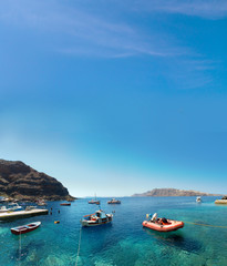 Fototapeta na wymiar boats at the fishing harbour village of Oia and Amoudi Bay in Santorini greek island clear meditoraiian clear blue waters and sky