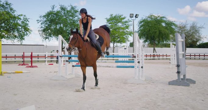 Girl horseback riding in equestrian course