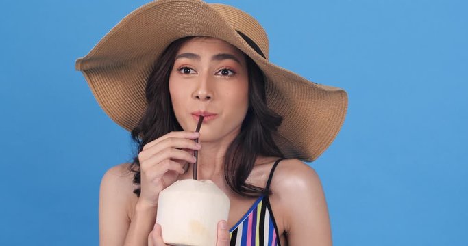 Portrait of beautiful asian woman sucking or drinking coconut water. Teenage girl holding coconut fruit on hand. Concept of beauty, celebration, shopping, fashion, food and entertainment. 4K UHD.