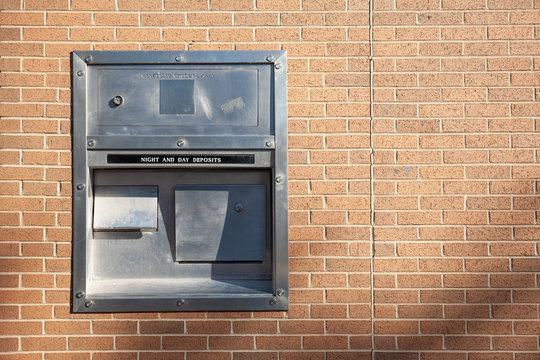 A Night And Day Deposit Box Drop Off On The Light Brown Brick Wall