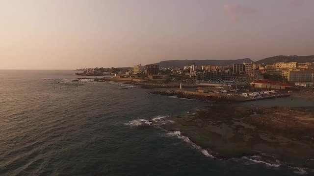 Aerial view of ocean waves breaking on shore at sunset, Batroun, Lebanon