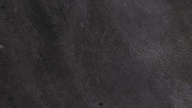 Pan across a granite countertop as a colorful splash of powered tumeric is thrown across the counter.