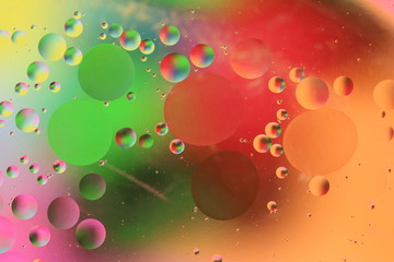 macro of oil mixed with water on colorful red, yellow, pink, green, blue background, colourful circles, copy space, vertical