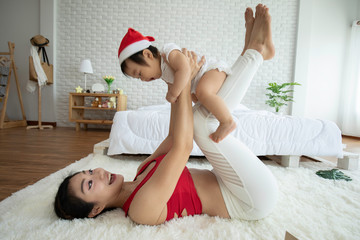 Obraz na płótnie Canvas Happy Beauty mother Holding Cute Sweet Adorable Asian Baby wearing white dress smiling and playing with happiness emotional in cozy bedroom,Healthy Baby Concept,Selective Focus