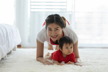 Fototapeta premium Attractive Mother Asian woman practice yoga with baby to meditation in bedroom after wake up in the morning Feeling so comfortable and relax,Yoga with Baby for Healthcare Concept