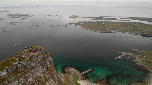 Aerial drone pan right and uprising motion of mountain climbers on top of the majestic Tr&aelig;nstaven in Northern Norway