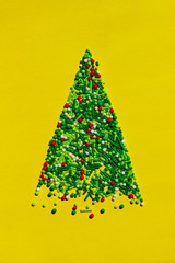 Vertical image of Christmas tree mades of colorful candies. Holidays, food, Christmas concept. Green Christmas tree on yellow background