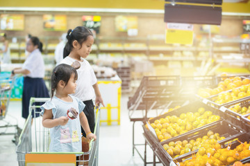 Asian children girls  shopping with choose to see orange in Department store.
