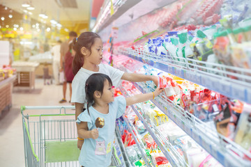 Asian children girl  on the cart shopping choose to see fresh food in department store.