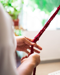 Hand of a craftsman knitting handmade macrame.
