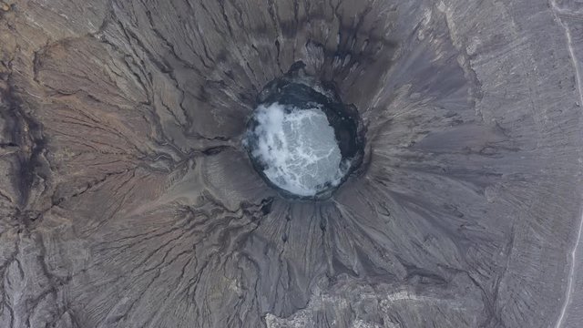 View from above, stunning aerial view of the Mount Bromo with clouds of gases raising from the crater. Mount Bromo is an active volcano in East Java, Indonesia.	