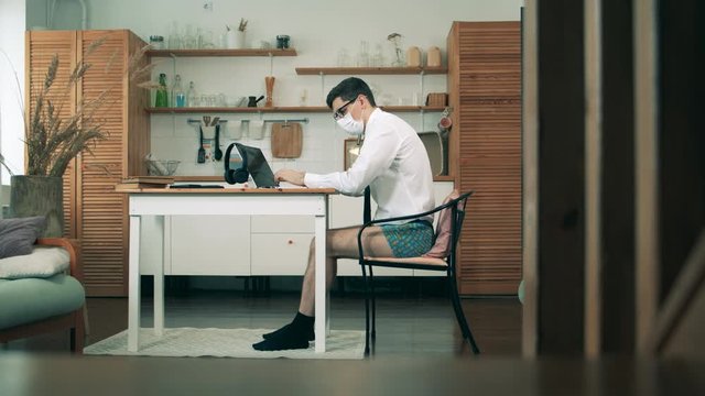 Workimg from home during coronavirus pandemic. A man with no pants on is working on a computer from home