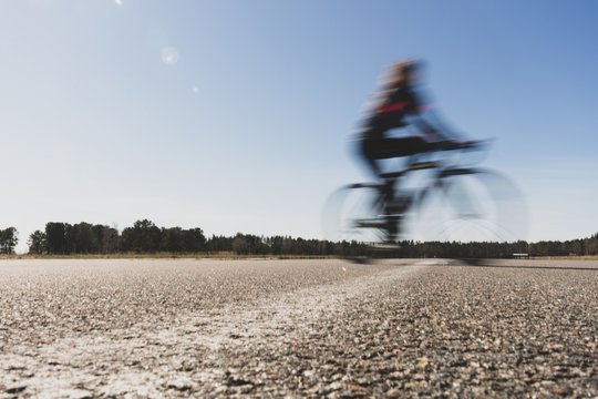 Blurred image of a woman cyclist on a sunny summer day. Healthy lifestyle and sports theme. Biker in motion 
