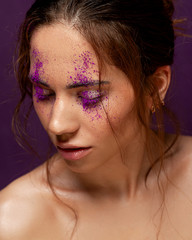 Portrait of a girl with an unusual and trendy make-up with bright-colored pigment scattered over her eyelids. Creative make up.