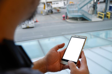 POV of an asian man while holding using a smartphone a mobile smart phone in airport terminal building in summer daytime. Business man while holiday.. Looking at smartphone.
