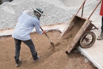 Construction workers are scooping sand for use in cement mixing