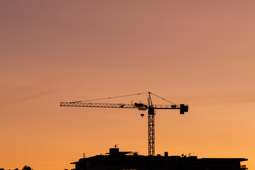 Silhouette of crane with orange sky.