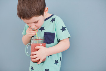 Cute toddler boy drink healthy smoothie from glass mason jar