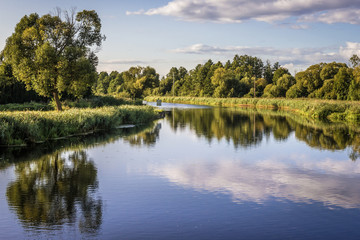 Fototapeta na wymiar Clouds reflecting in the Biebrza River, view from Debowo Lock near Debowo village, Poland